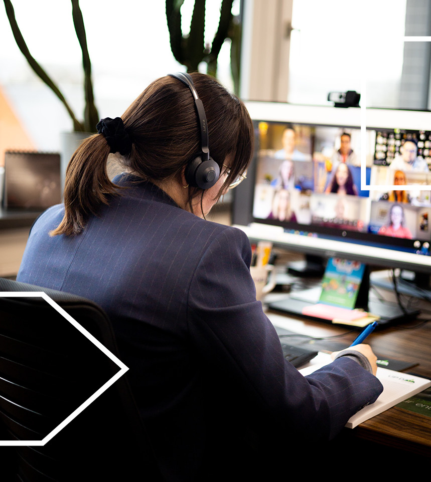 Mitarbeiterin in einer Videokonferenz am Schreibtisch.
